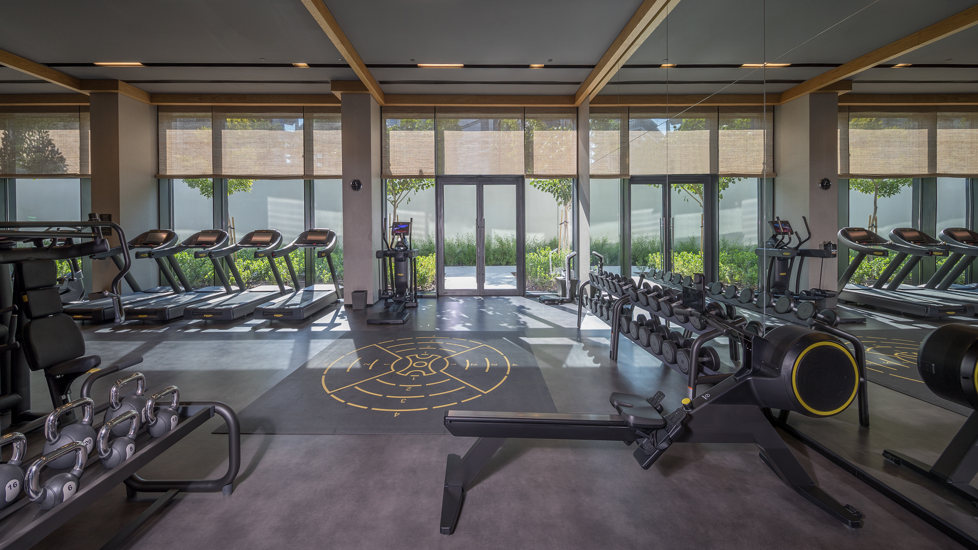 Gym equipment on display in a well-lit space, featuring treadmills and weights, Banyan Tree Dubai.